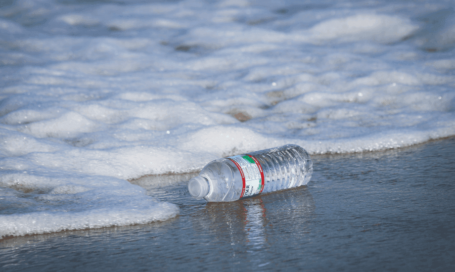 A full plastic bottle washed out on the beach
